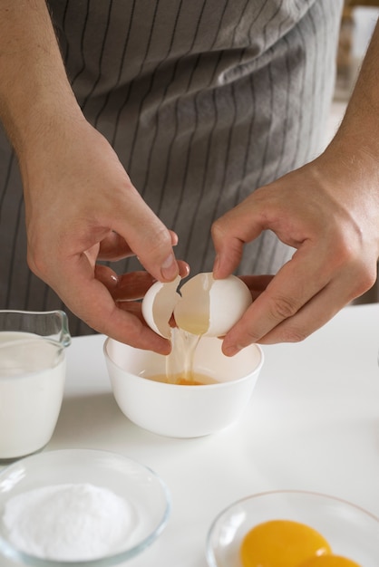 Foto grátis vista frontal cozinheiro quebrando ovo