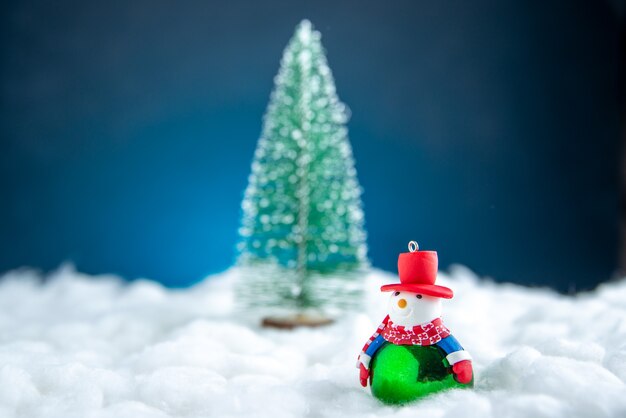 Vista frontal da árvore de natal do boneco de neve pequeno na superfície branca e azul