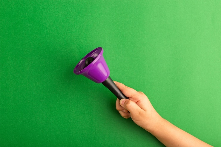 Foto grátis vista frontal da criança segurando um sino roxo na superfície verde