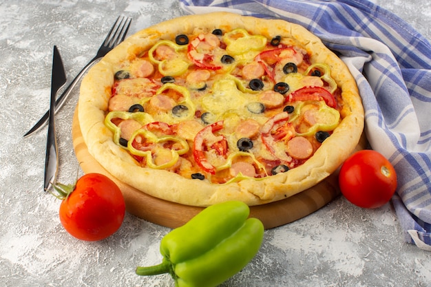 Vista frontal da deliciosa pizza de queijo com azeitonas, salsichas e tomates