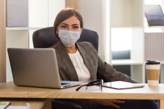 Vista frontal da empresária com máscara facial no escritório