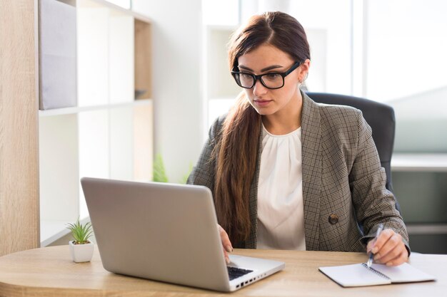 Vista frontal da empresária trabalhando em um laptop no escritório