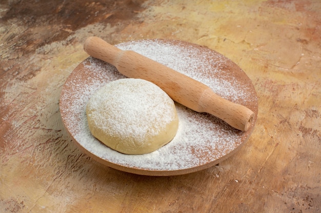 Vista frontal da fatia de massa crua com farinha em um prato de mesa de creme cozinha massa