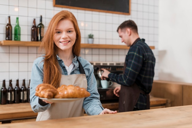 Vista frontal da garota barista com croissants