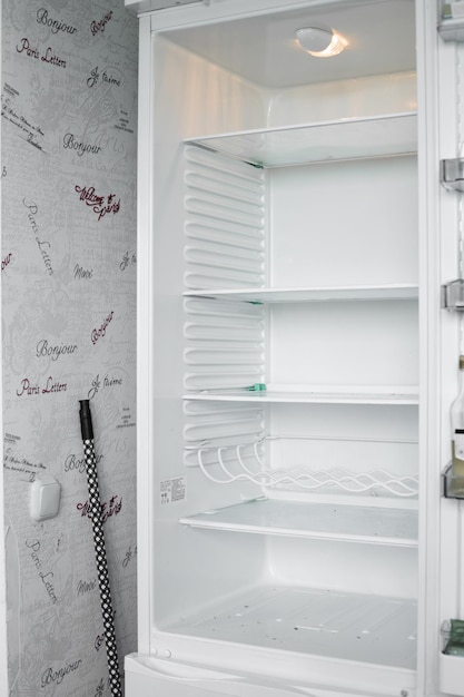 Vista frontal da geladeira vazia em casa Congelador moderno branco sem alimentos vegetais e frutas em casa Geladeira elétrica com várias prateleiras Conceito de aparelho e refrigerador