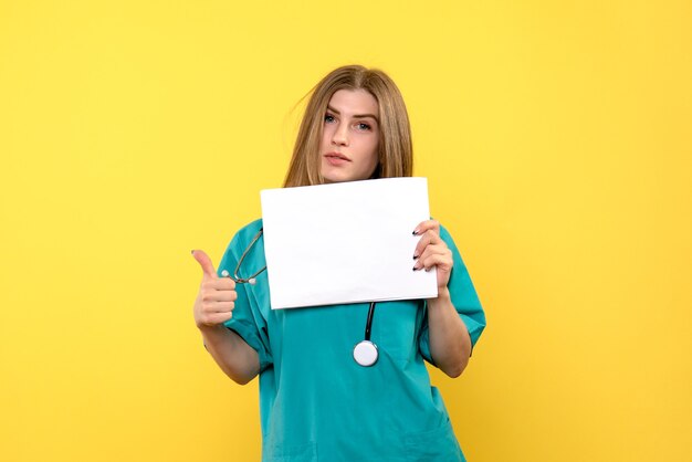 Vista frontal da jovem médica segurando arquivos no hospital médico de doenças do assoalho amarelo