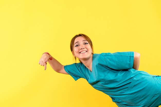 Vista frontal da jovem médica sorrindo na parede amarela