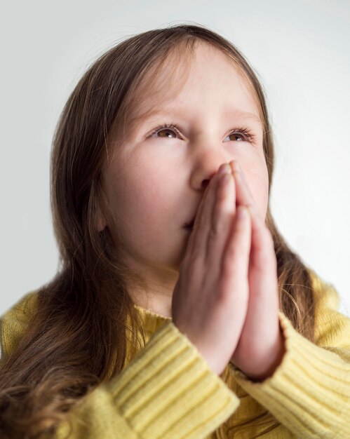 Vista frontal da linda garotinha rezando