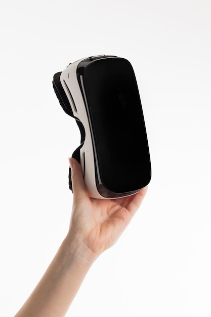 Vista frontal da mão segurando um fone de ouvido de realidade virtual