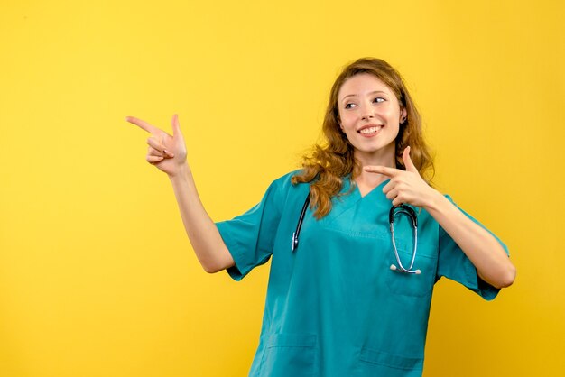 Vista frontal da médica apenas sorrindo na parede amarela