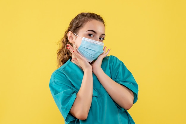 Vista frontal da médica com máscara e camisa médica, uniforme de saúde, vírus covid pandemia de cor