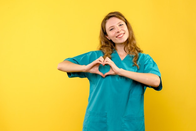 Foto grátis vista frontal da médica enviando amor na parede amarela