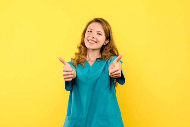 Vista frontal da médica sorrindo na parede amarela