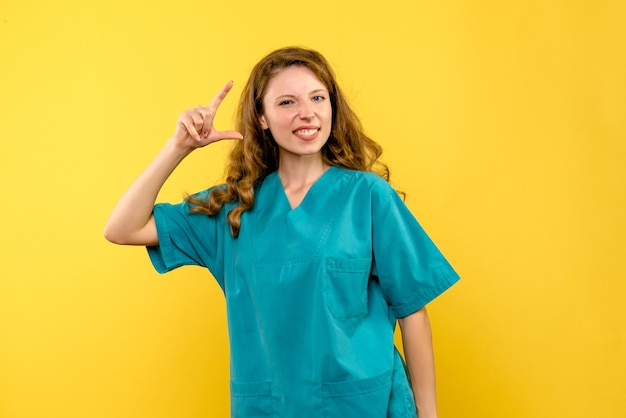 Vista frontal da médica sorrindo na parede amarela