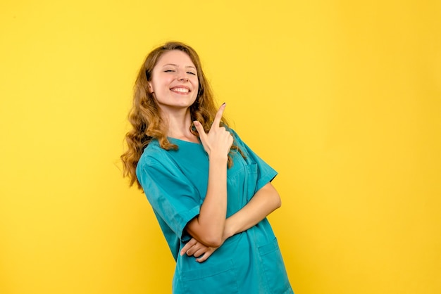 Vista frontal da médica sorrindo na parede amarela