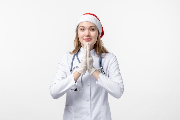 Vista frontal da médica sorrindo na parede branca