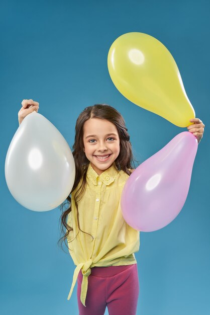 Vista frontal da menina alegre, mantendo balões coloridos