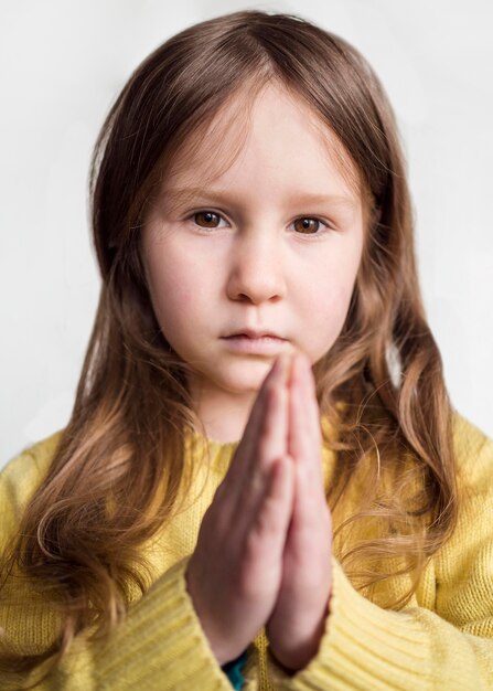 Vista frontal da menina bonitinha rezando
