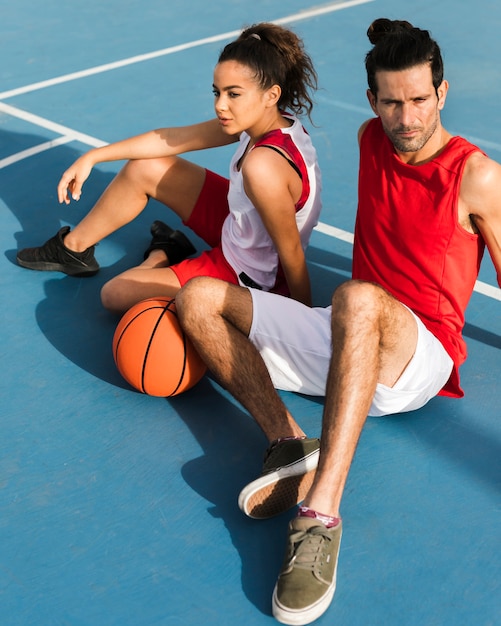 Vista frontal da menina e menino com bola de basquete