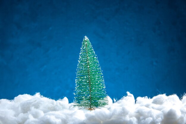 Vista frontal da mini árvore de natal em fundo branco azul