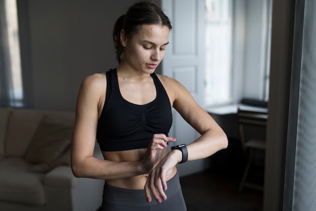 Vista frontal da mulher em athleisure olhando para seu smartwatch