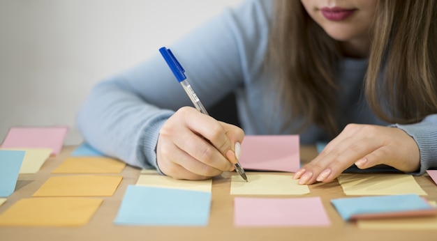 Vista frontal da mulher escrevendo em notas autoadesivas no escritório