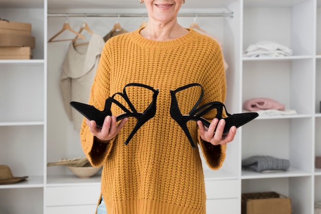 Foto grátis vista frontal da mulher madura, sorrindo e segurando o par de sapatos nas mãos