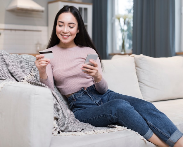 Vista frontal da mulher no sofá, fazer pedidos on-line usando cartão de crédito