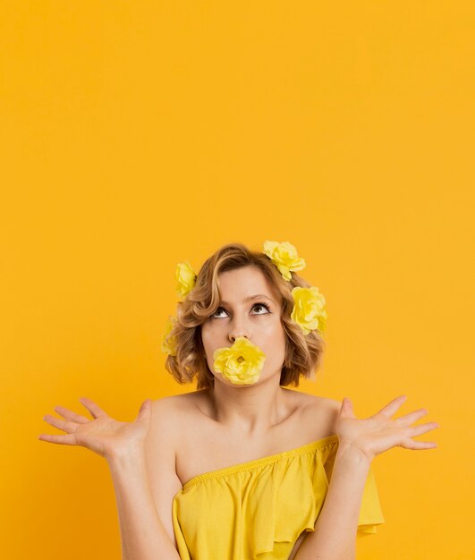 Vista frontal da mulher posando com flor cobrindo a boca