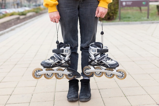 Vista frontal da mulher segurando patins em cada mão