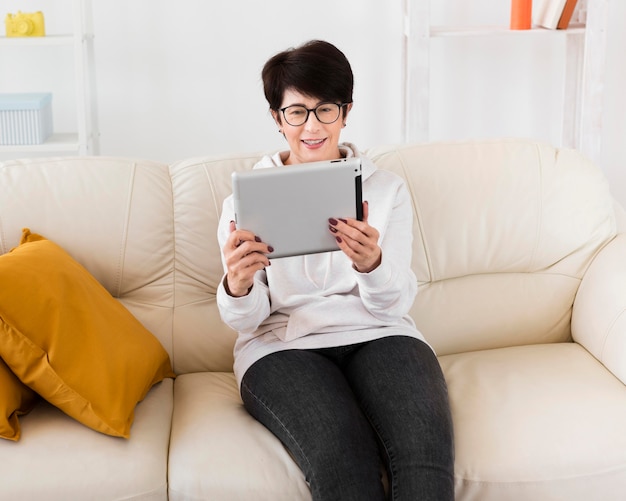 Vista frontal da mulher sentada no sofá com tablet