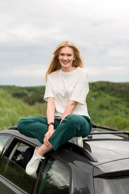 Vista frontal da mulher sorridente em pé no carro