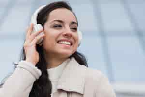 Foto grátis vista frontal da mulher sorridente, ouvindo música em fones de ouvido