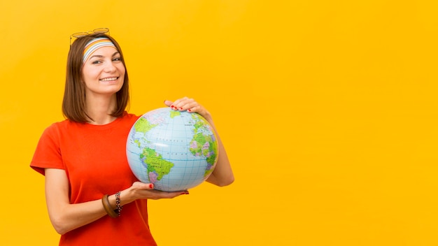 Vista frontal da mulher sorridente segurando o globo com espaço de cópia