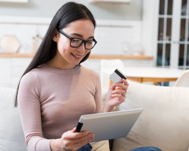 Vista frontal da mulher sorridente segurando o tablet e cartão de crédito