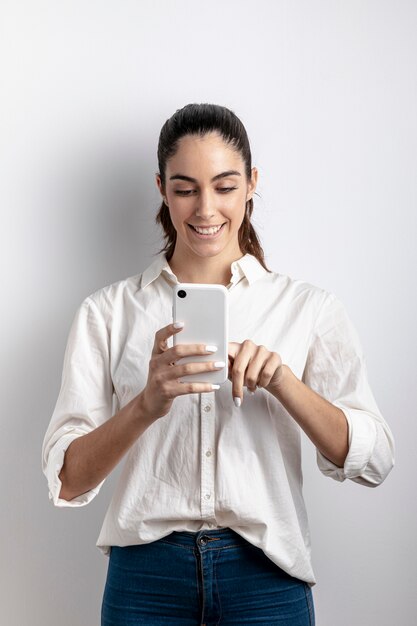 Vista frontal da mulher sorrindo e segurando o smartphone