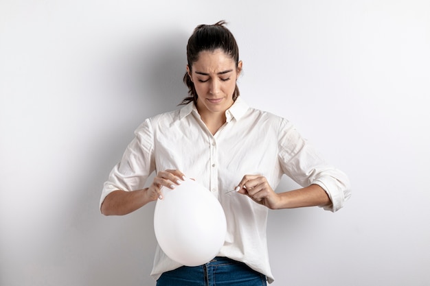Foto grátis vista frontal da mulher tentando estourar um balão