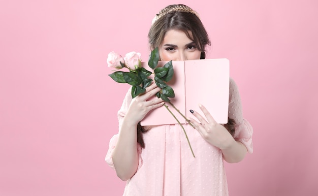 Vista frontal da mulher tímida segurando rosas e livro