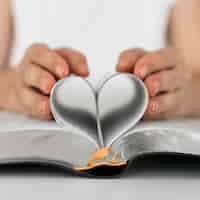 Foto grátis vista frontal da pessoa fazendo coração de páginas do livro sagrado