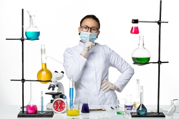 Foto grátis vista frontal da química feminina em traje médico usando máscara em pé sobre fundo branco claro laboratório de química de vírus covid- respingo