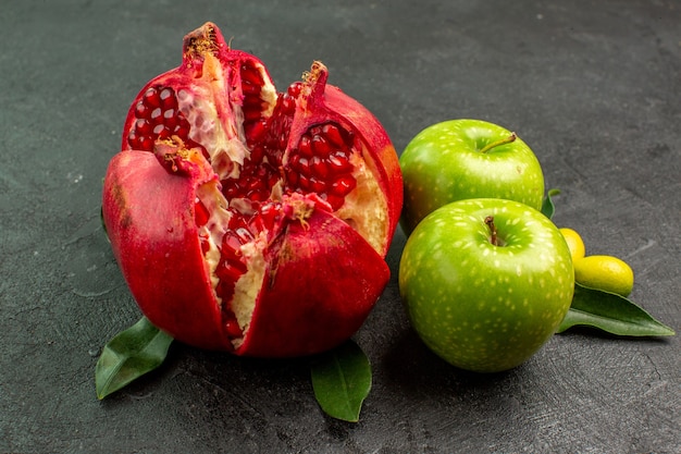 Vista frontal da romã fresca com maçãs verdes na superfície escura, cor de frutas maduras