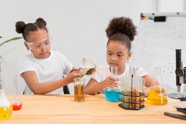 Vista frontal das meninas experimentando química com tubos e poções