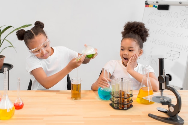 Vista frontal das meninas se divertindo com experimentos de química