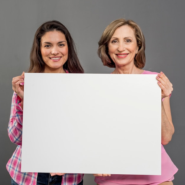 Vista frontal das mulheres segurando a folha de papel em branco