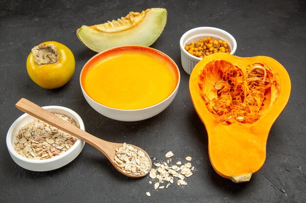 Vista frontal de abóbora fresca com sopa de abóbora em uma mesa cinza escuro cor de sopa de frutas maduras