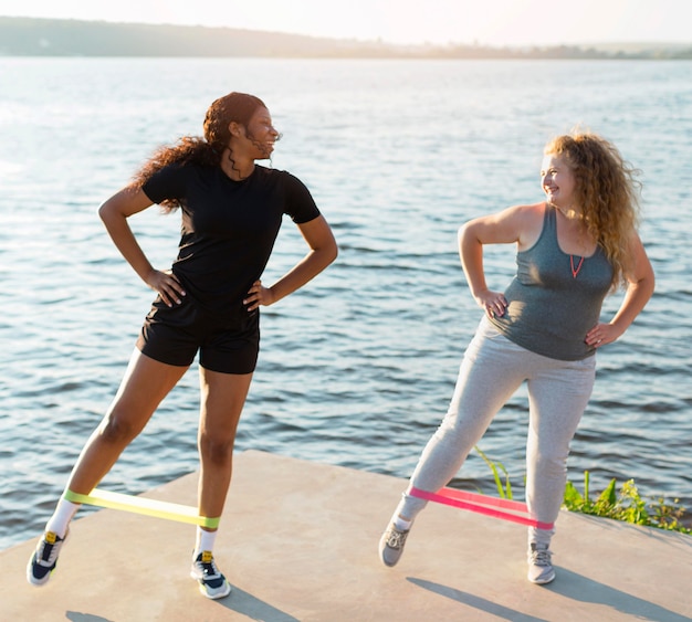 Vista frontal de amigas fazendo exercícios à beira do lago