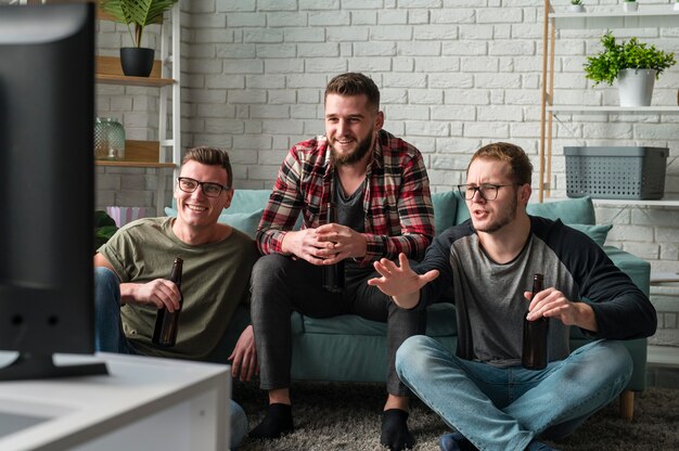 Vista frontal de amigos do sexo masculino assistindo esportes na tv