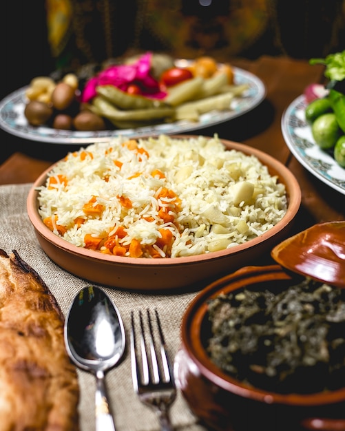 Vista frontal de arroz cozido em um prato com batatas cozidas e abóbora