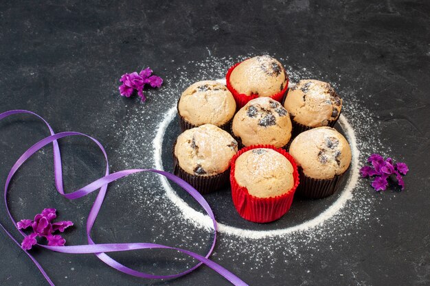 Vista frontal de bolinhos deliciosos com chocolate na mesa escura