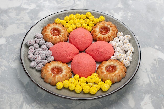 Foto grátis vista frontal de bolos rosa com doces e biscoitos dentro do prato na superfície branca